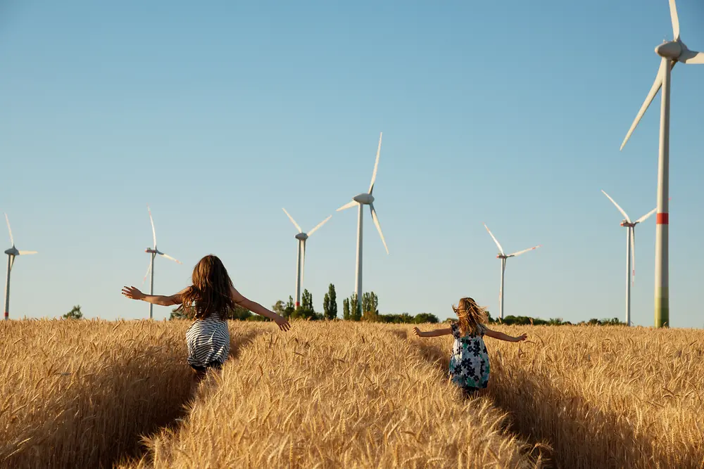 two girls running through wheat fields